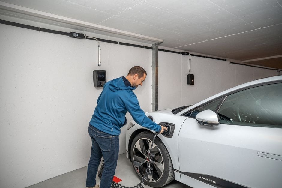Conducteur branchant une voiture électrique sur borne de recharge rapide
